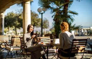 two women sitting at an outdoor table eating food at Hotel Bellevue - Liburnia in Opatija