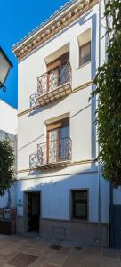 a white building with two balconies and two windows at Casa Rural "El Paseo del libro" in Sabiote