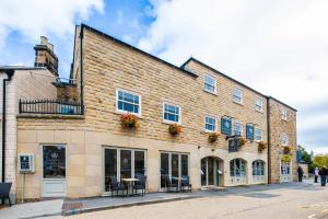 un gran edificio de ladrillo con mesas y sillas al aire libre en The H Boutique Hotel en Bakewell