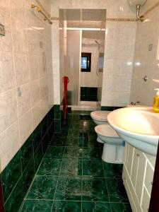 a green tiled bathroom with two toilets and a sink at La Residenza dei Papi in Papigno