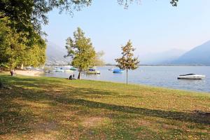 a park next to a lake with boats in the water at Appartamento Ca dal Tilo in Minusio