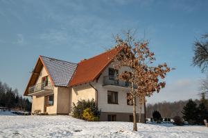 uma casa com um telhado vermelho na neve em Wypoczynek na Kaszubach przy jeziorach i lasach em Mokrzyn
