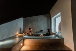 Ein Mann und eine Frau sitzen in einer Badewanne in der Unterkunft The Saint Vlassis in Naxos Chora