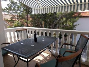 a black table with wine glasses on a balcony at Bosi i Goli in Starigrad-Paklenica