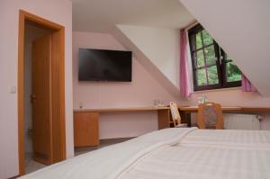 a bedroom with a bed and a tv on the wall at Waldfrieden Waldheim in Waldheim