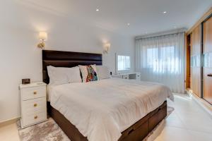 a white bedroom with a large bed and a window at Carvoeiro Bay Apartment in Carvoeiro +12 photos