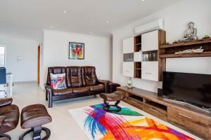 a living room with leather furniture and a flat screen tv at Carvoeiro Bay Apartment in Carvoeiro