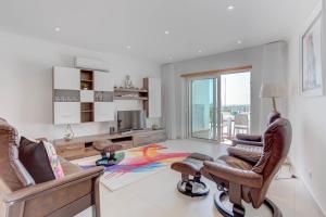 a living room with two chairs and a desk and a television at Carvoeiro Bay Apartment in Carvoeiro
