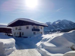 ein schneebedecktes Gebäude mit Bergen im Hintergrund in der Unterkunft Ferienhaus Sonnberg in Fieberbrunn