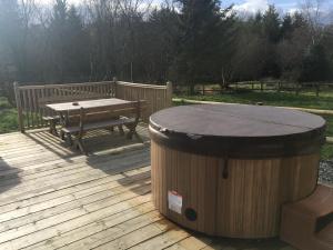 eine Holzterrasse mit einem Tisch und einem Holzfass in der Unterkunft Brynllwyd Glamping in Devils Bridge