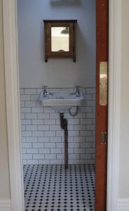 a bathroom with a sink and a mirror at Entwhistle Cottage in Christchurch