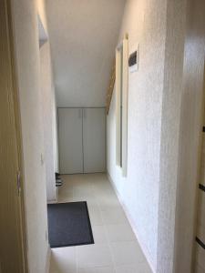 a hallway with a white tile floor and a white wall at AV Apartment in Rēzekne