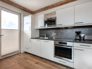 a white kitchen with white cabinets and a window at Apartment Kristall in Finkenberg