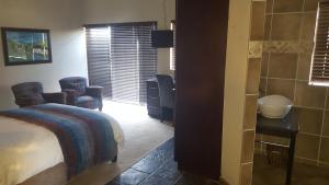 ein Schlafzimmer mit einem Bett und 2 Stühlen sowie ein Badezimmer in der Unterkunft House Haven Guesthouse in Port Elizabeth