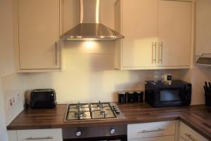 a kitchen with a stove top oven next to a microwave at Kelpies Serviced Apartments-McKay in Falkirk