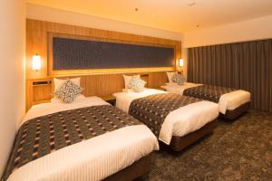 Art Hotel Morioka في موريوكا: غرفة في فندق بثلاث اسرة في غرفة
