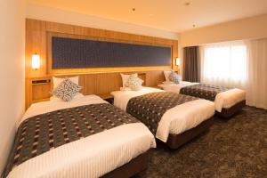 a hotel room with three beds in a room at Art Hotel Morioka in Morioka