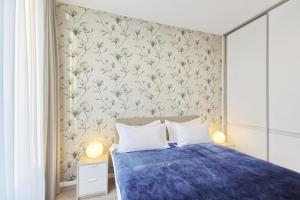 a bedroom with a blue bed with a floral wallpaper at Asian Magnolia Boutique Apartments in Druskininkai