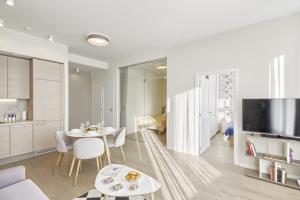 uma sala de estar com uma mesa e cadeiras e uma televisão em Asian Magnolia Boutique Apartments em Druskininkai