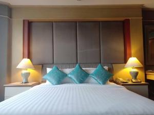 a bedroom with a large bed with blue pillows at The Maruay Garden Hotel in Bangkok