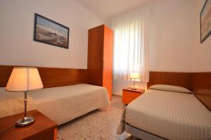 Habitación de hotel con 2 camas y ventana en Appartamenti Dei Pini, en Bibione