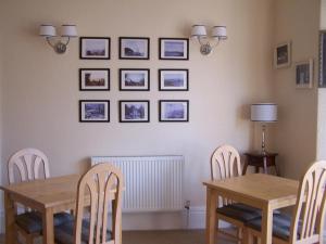 een eetkamer met twee tafels en stoelen en foto's aan de muur bij The Carmen Guesthouse in Llandudno