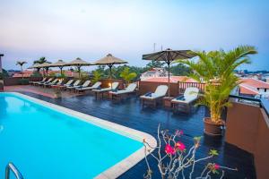 una piscina de hotel con tumbonas y sombrillas en City River Hotel en Siem Reap