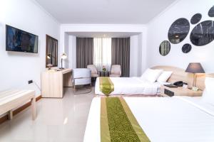 a hotel room with two beds and a desk at The Maruay Garden Hotel in Bangkok