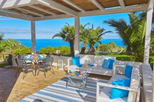 a patio with a table and chairs and the ocean at Villa Gaia - Scopello-Villas in Scopello