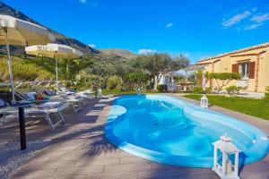 una grande piscina blu con sedie e ombrelloni di Villa Gaia - Scopello-Villas a Scopello