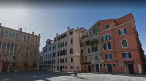 a person walking in front of some buildings at La Tana Cozy Apartment in Campo San Maurizio in Venice
