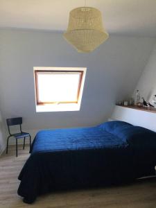 Un dormitorio con una cama azul y una ventana en LA MAISON DE LA PLAGE BEG LEGUER, en Lannion