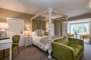 a bedroom with a canopy bed and a green couch at Heacham Manor Hotel in Hunstanton