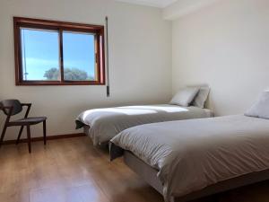 twee bedden in een kamer met een stoel en een raam bij VMO Apartment in Vila do Conde