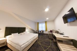 a bedroom with a bed and a desk and a tv at Hotel Valcha in Prague