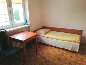 a small bedroom with a bed and a desk and a window at Willa Ewa in Warsaw