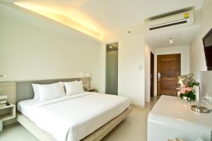 a white bedroom with a bed and a desk at Sunshine Hotel & Residences in Pattaya Central