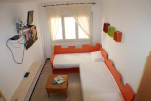 ロザスにあるAgi Sant Antoniのオレンジ色のソファとテーブルが備わる小さな客室です。