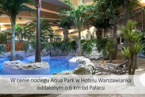 a hotel lobby with a swimming pool with palm trees at Pałac Zegrzyński in Zegrze