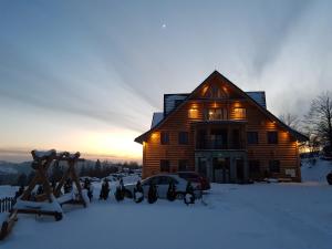 a log cabin in the snow with the sun setting at Dwór Bogdałów in Koniaków +5 photos