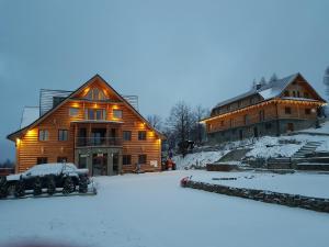 a large wooden house with a car parked in the snow at Dwór Bogdałów in Koniaków