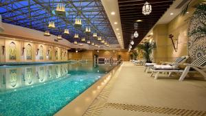 a large swimming pool in a hotel with chairs at Pullman Dalian in Dalian