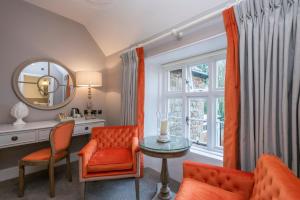 a living room with orange chairs and a table and a mirror at Heacham Manor Hotel in Hunstanton