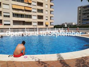 a man sitting in a swimming pool in front of a building at Playa 500m y Centro Pueblo 600m, Piscina, 4 Clim, 2 Parkings in Santa Pola