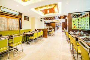 a dining room with tables and yellow chairs at FabHotel Prime Sanket Inn, Phoenix Mall in Pune