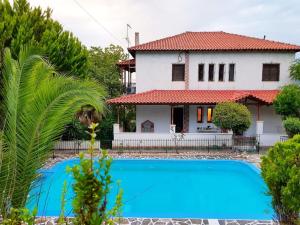 a house with a blue swimming pool in front of a house at Ancient Olympia Luxury Pool Villa Palace 4Bedroom in Olympia