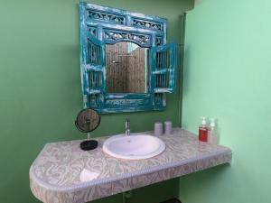 een badkamer met een wastafel met een blauwe spiegel bij Blue Coco in Keramas