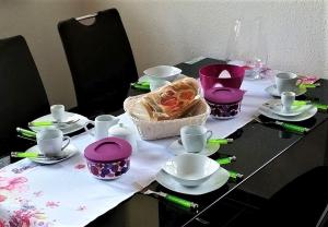 a table with plates and cups and a basket of food at Ferienwohnung-4you in Sigmarszell