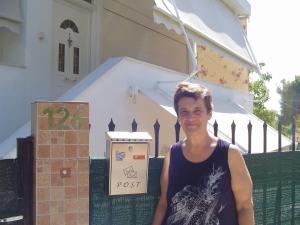 a man standing in front of a post sign at Nina Rooms (apartments) in Artemida