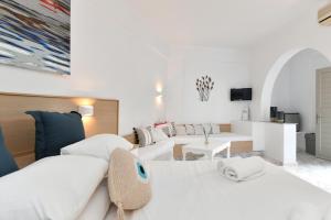 a white room with two beds and a table at Sunset View Hotel in Parikia